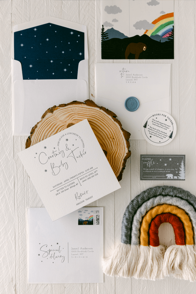 Woodland-themed baby boy shower letterpress invitation suite featuring a custom starry night envelope liner and wax seals. The design includes rustic wood elements, hand-painted rainbow edges, and a vellum overlay with forest animals, creating an enchanting woodland atmosphere.