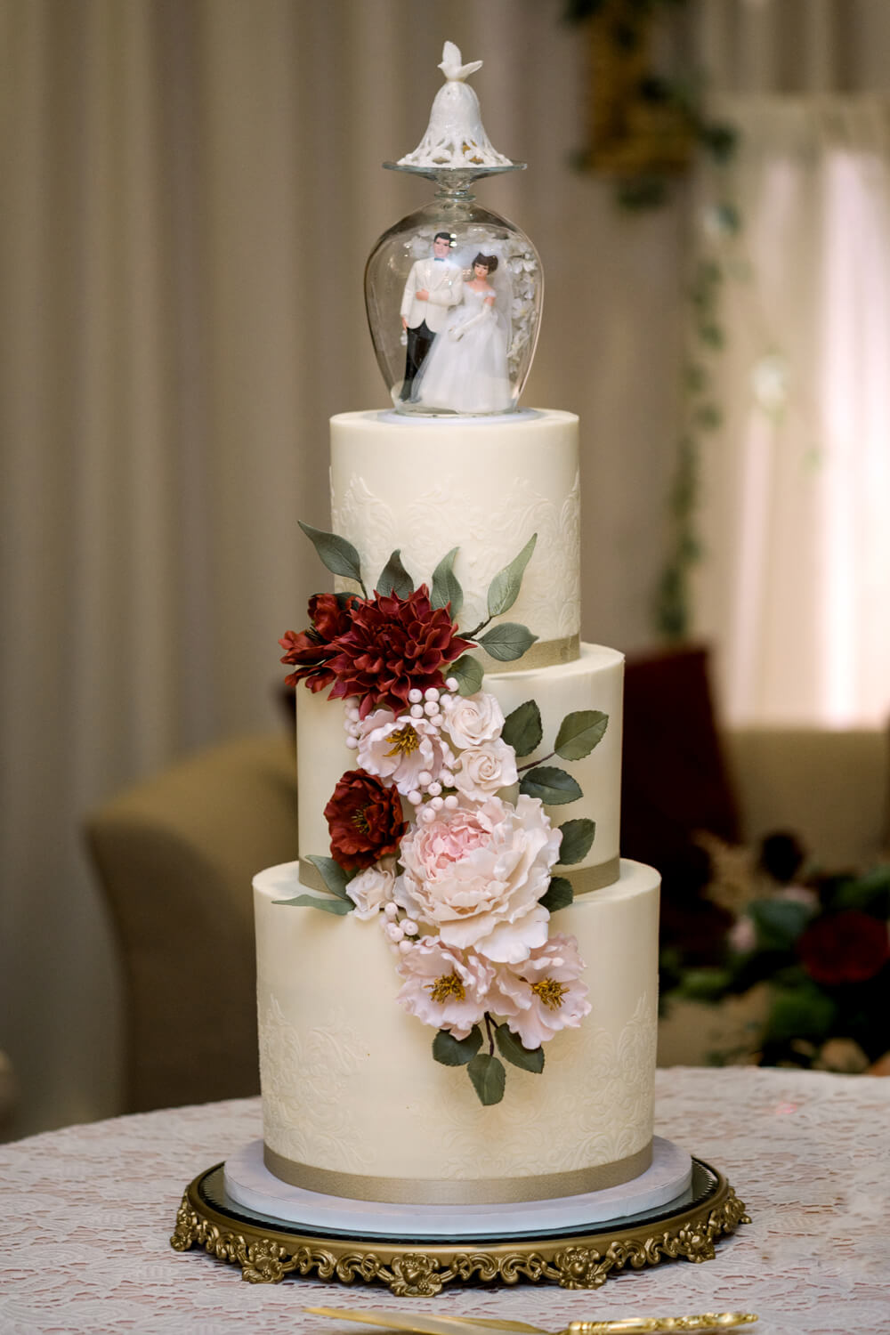 Celebrating 50 Years of Love: Our Parents' Golden Anniversary 26 Four-tier white anniversary cake with burgundy and blush sugar flowers, designed for a Victorian-inspired 50th anniversary celebration.