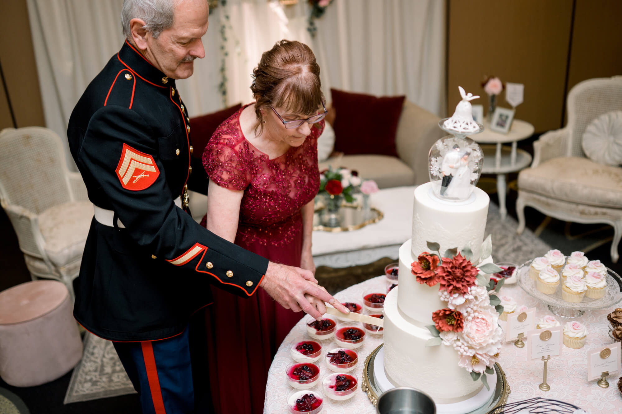 Celebrating 50 Years of Love: Our Parents' Golden Anniversary 25 Couple celebrating 50 years of marriage cutting their anniversary cake, topped with their original wedding topper, surrounded by desserts and Victorian-inspired décor.