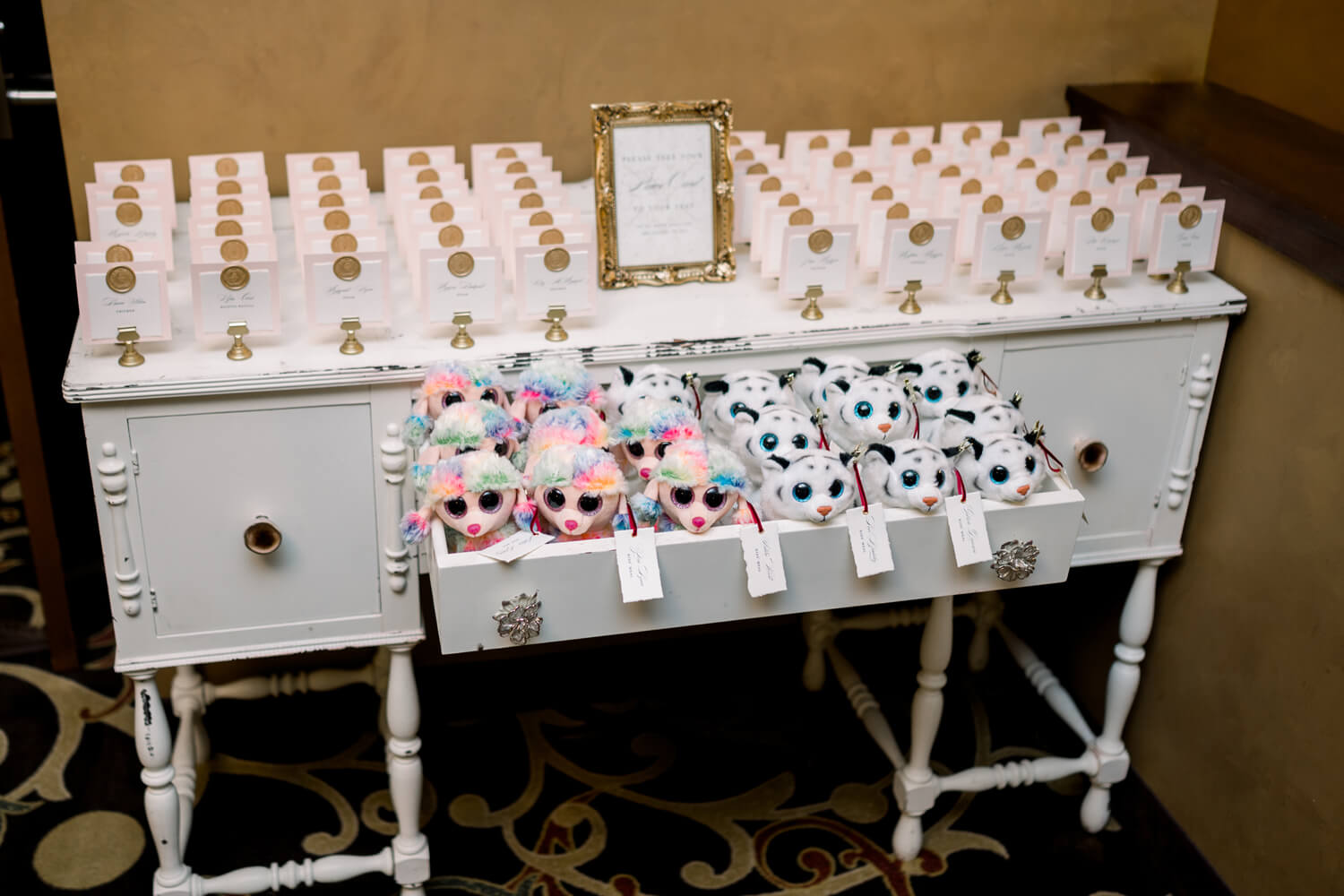 Celebrating 50 Years of Love: Our Parents' Golden Anniversary 18 Escort card table at a 50th anniversary celebration featuring custom name cards and plush animal favors for kids,