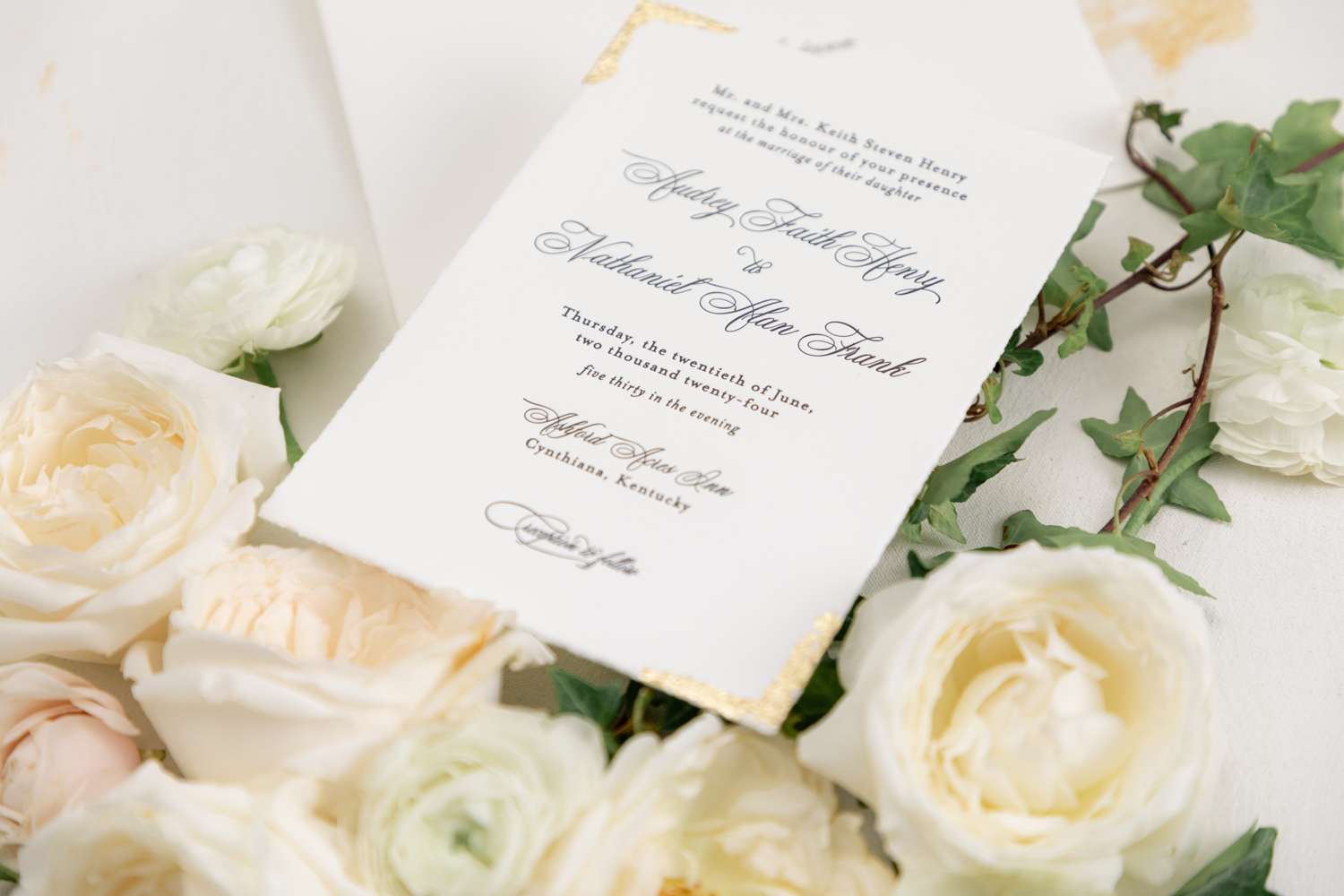 Black and White Wedding Invitations for a Classic Ashford Acres Inn Wedding 4 Close-up of a black and white wedding invitation with classic script, gold foil detail in the corner, and Ashford Acres Inn as the listed venue, styled with delicate garden roses and ranunculus.
