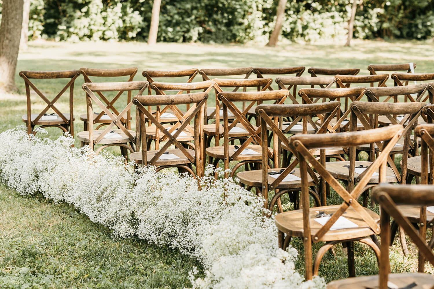 Black and White Wedding Invitations for a Classic Ashford Acres Inn Wedding 16 Close-up of wooden ceremony chairs with black and white wedding programs, framed by low clouds of baby’s breath flowers along the aisle.