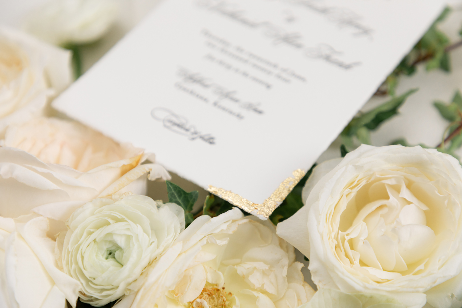 Black and White Wedding Invitations for a Classic Ashford Acres Inn Wedding 1 Close-up of black and white letterpress wedding invitation with gold foil corner detail, surrounded by soft ivory and white roses and ranunculus.