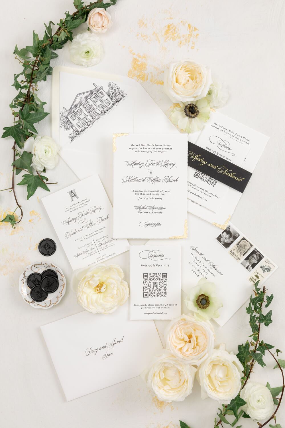 Black and White Wedding Invitations for a Classic Ashford Acres Inn Wedding 6 Flat lay of black and white wedding invitations with gold foil corners, custom Ashford Acres Inn envelope liner, black wax seals, and RSVP card with QR code, styled with ivory flowers and trailing ivy.