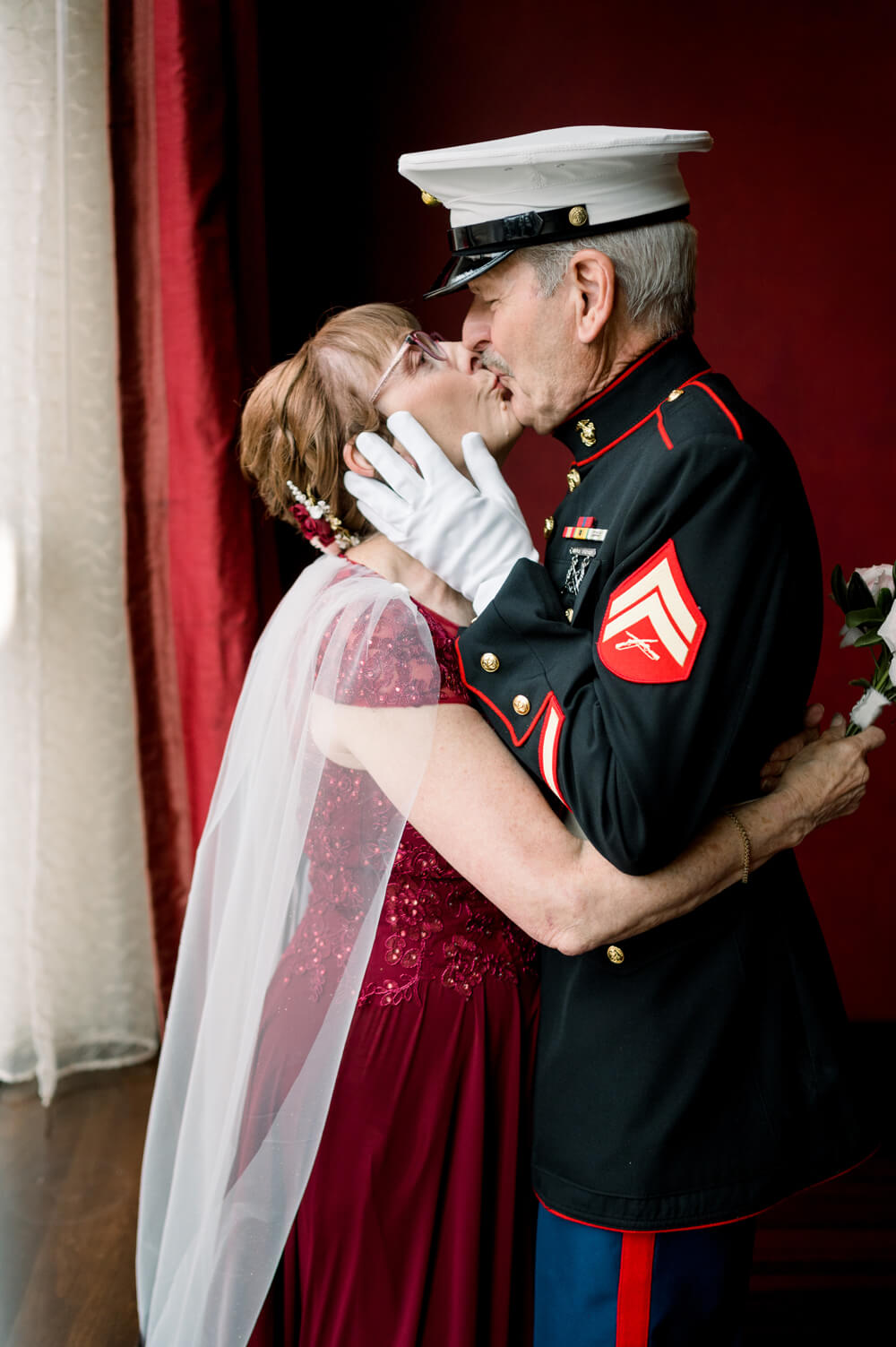 Celebrating 50 Years of Love: Our Parents' Golden Anniversary 44 A sweet kiss between a couple celebrating their 50th wedding anniversary, with the husband in Marine Corps dress blues and the wife in a burgundy gown.