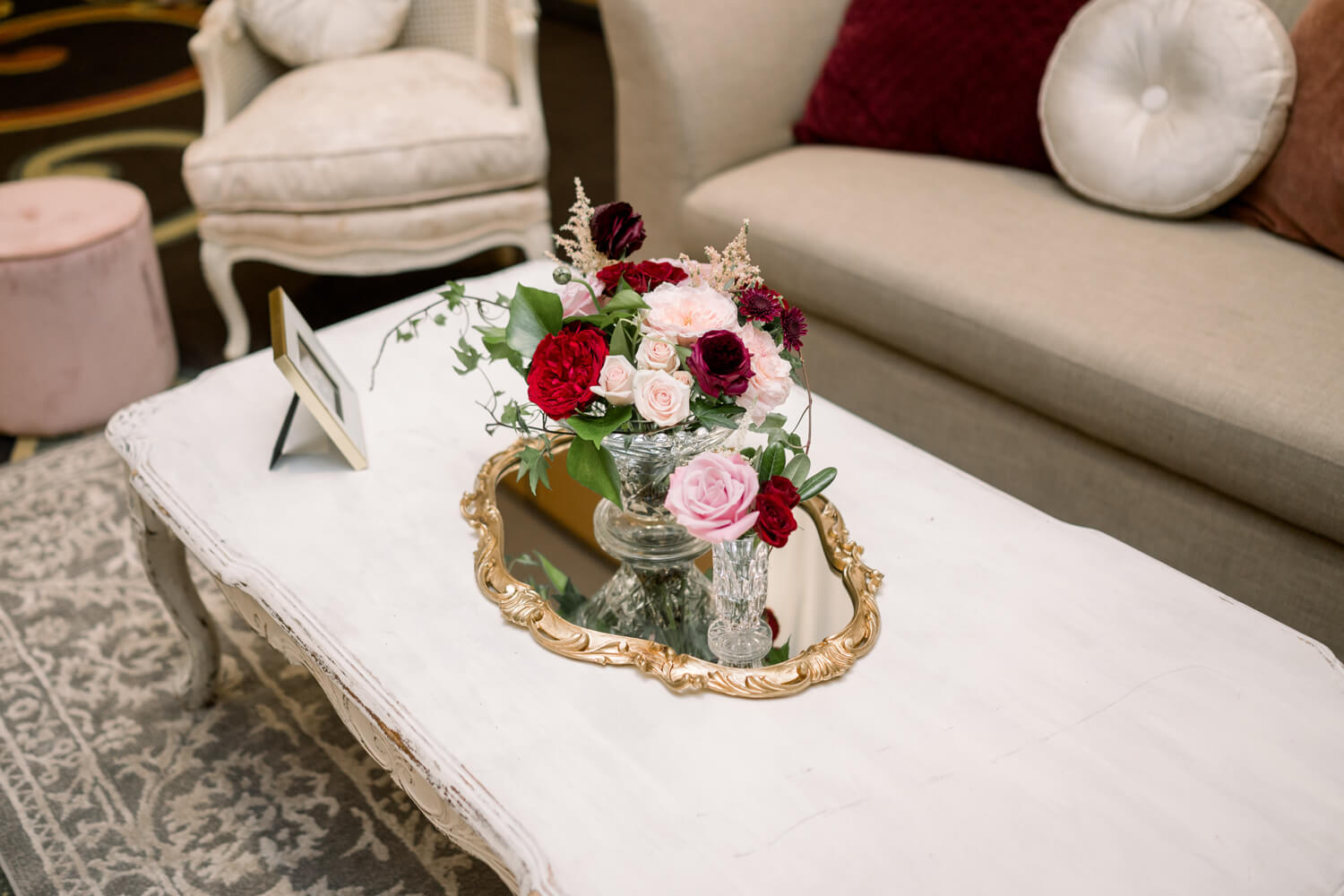 Celebrating 50 Years of Love: Our Parents' Golden Anniversary 10 Victorian-inspired floral centerpiece with blush, red, and pink roses on a white vintage coffee table, styled for a 50th wedding anniversary lounge area celebrating 50 years of love.