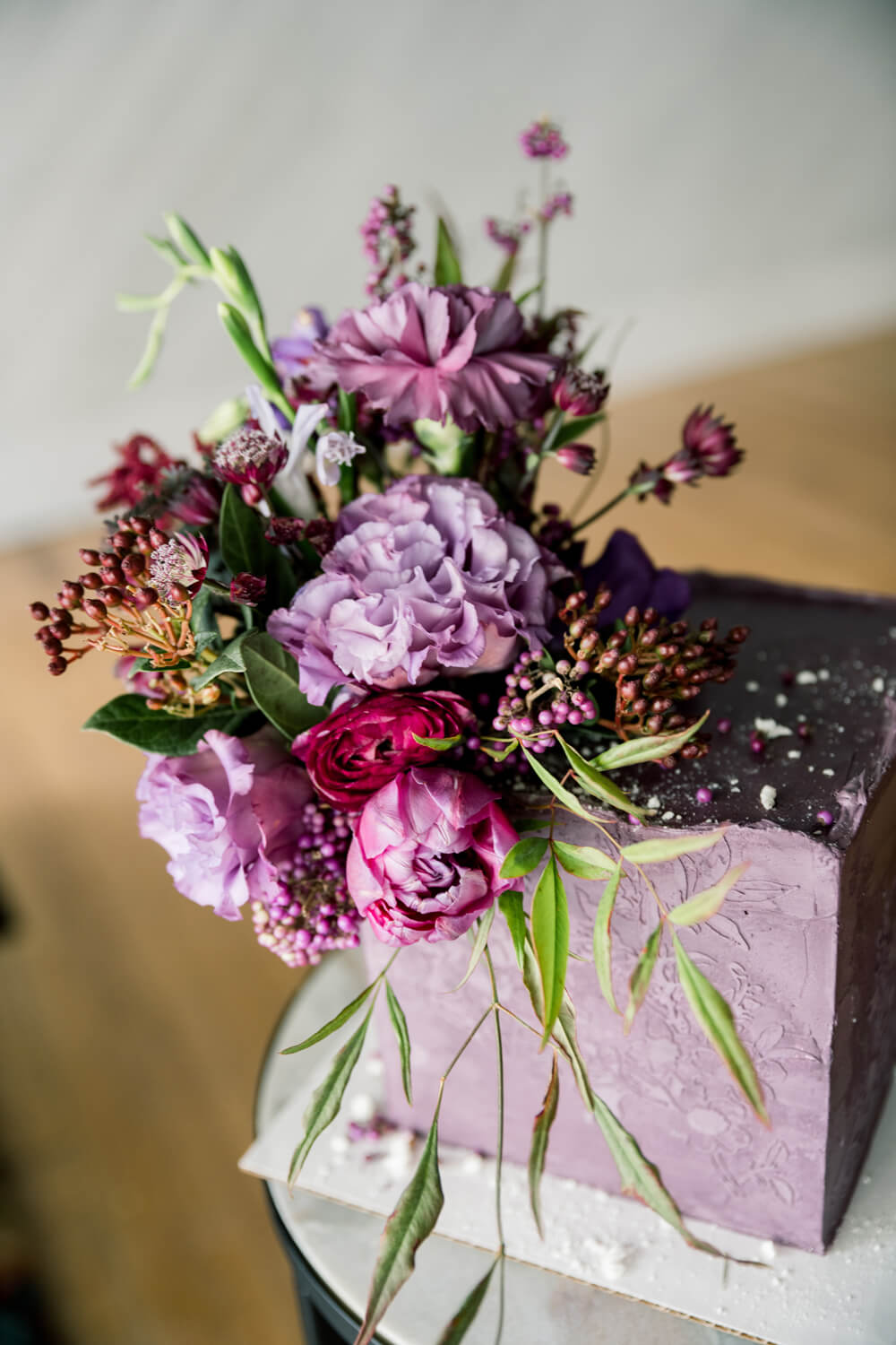 Bold Jewel Tone Wedding Invitations: Burgundy and Purple Wedding Inspiration 14 A square purple wedding cake decorated with textured floral buttercream and topped with vibrant jewel-toned flowers including lisianthus, peonies, and berries.