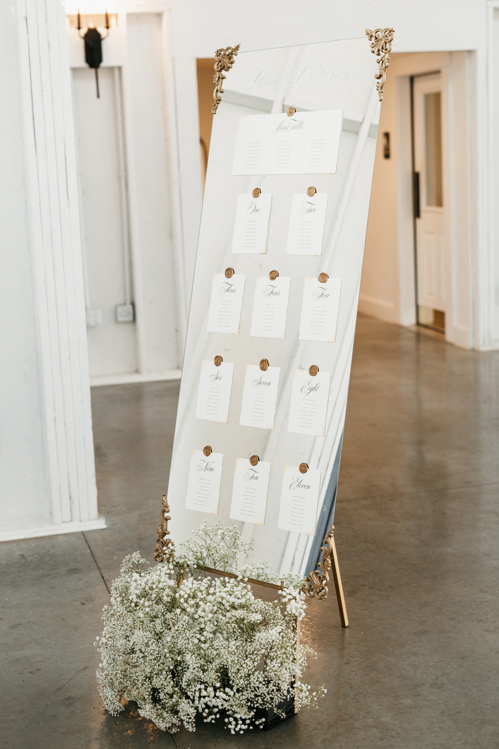 Black and White Wedding Invitations for a Classic Ashford Acres Inn Wedding 28 Gold-framed mirror seating chart with wax-sealed cards and gold detailing, styled with baby’s breath at the base.
