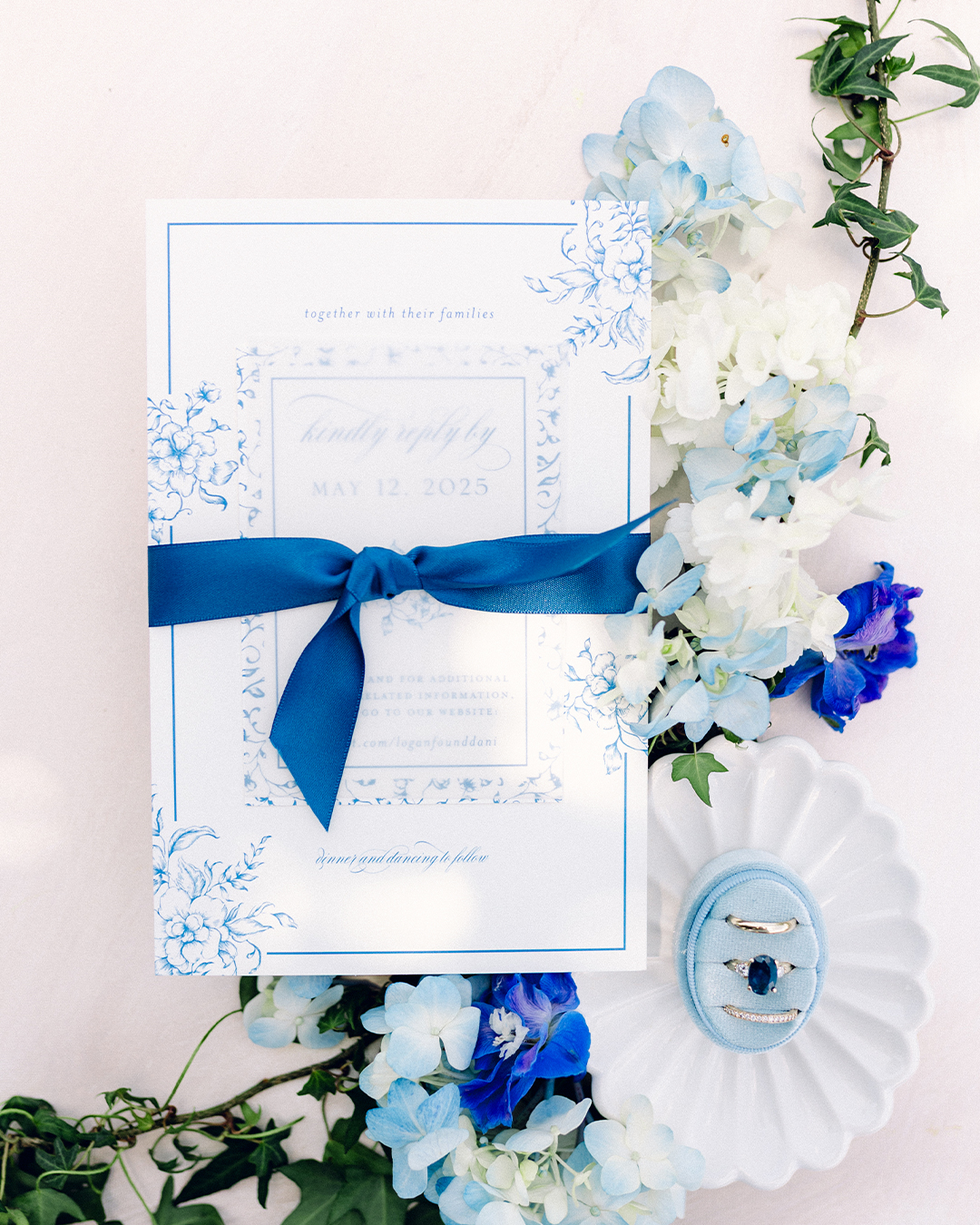 Flatlay of a wedding invitation suite tied with a blue silk ribbon, communicating what kind of celebration the guests can expect for a seamless wedding guest experience.