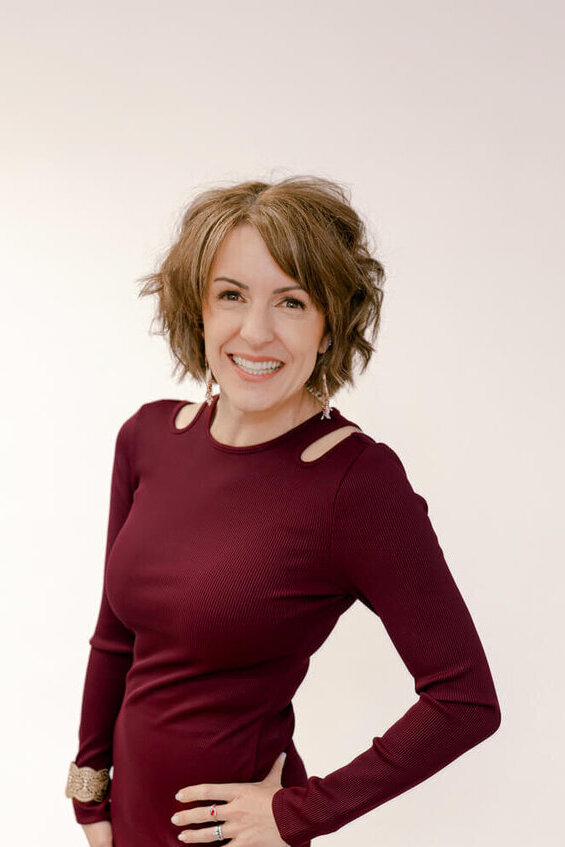 How to Choose a Stationery Designer When “Pretty” Isn’t Enough 5 Custom wedding statinonery designer Janeil Anderson of Seventh and Anderson stands against a clean, neutral backdrop in a deep burgundy dress, smiling with calm confidence.