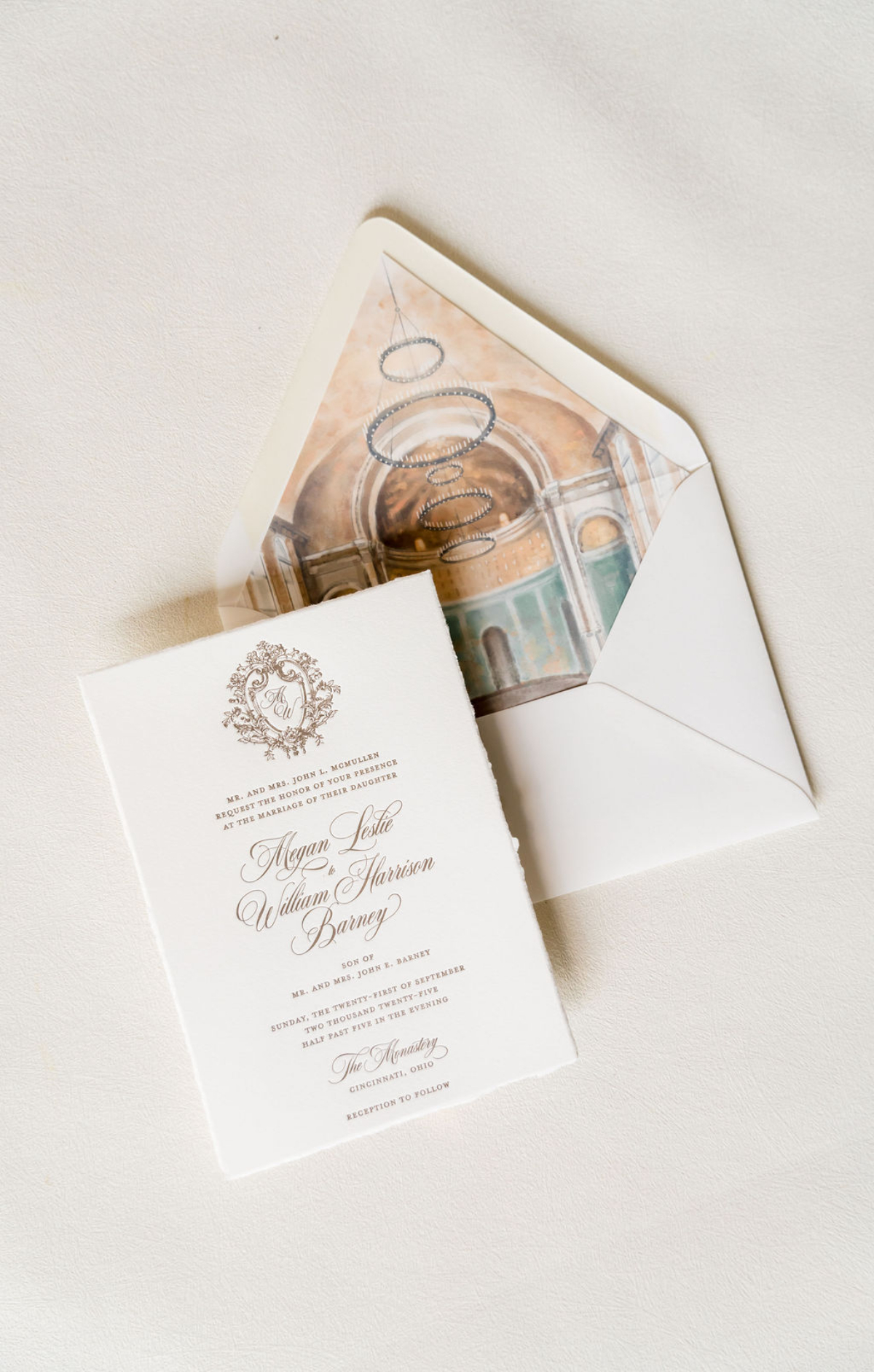 Choosing Your Wedding Invitation Style 3 Elegant wedding invitation partially pulled from an envelope, revealing a printed photo of a grand ceremony space inside the envelope lining, styled on a neutral textured background.