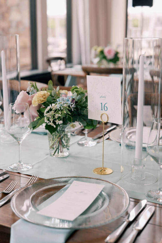 Pastel wedding tablescape with flowers, floral table numbers, and wedding menus sitting on a glass charger for a Moonlight Basin wedding in Big Sky, Montana 