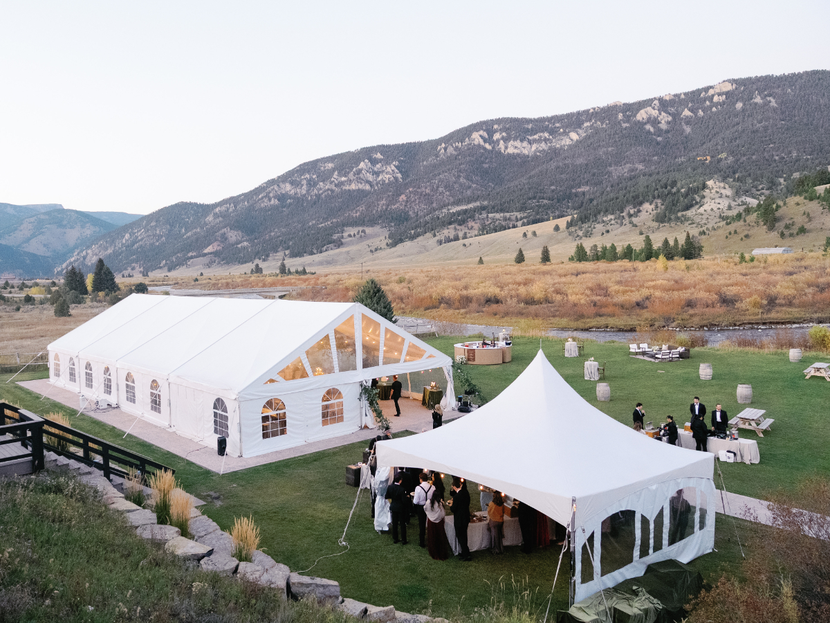 Large white tents set up for a wedding reception against a mountainous backdrop, highlighting event logistics that hiring a wedding planner can simplify.