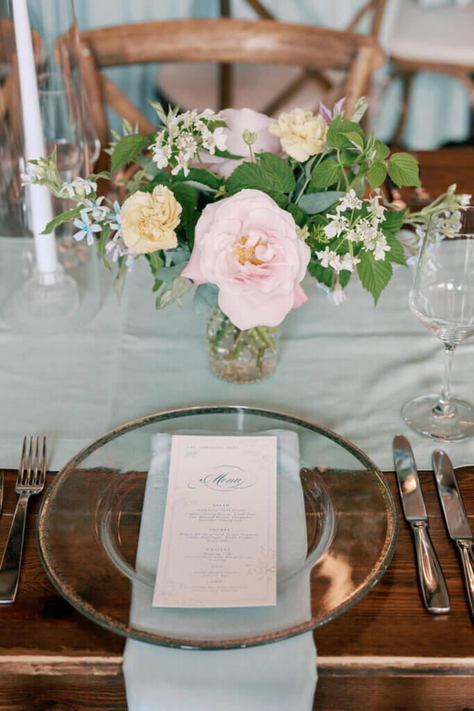 Floral wedding menus, pastel wedding flower arrangement, and glass charger for a Moonlight Basin in Big Sky, MT.