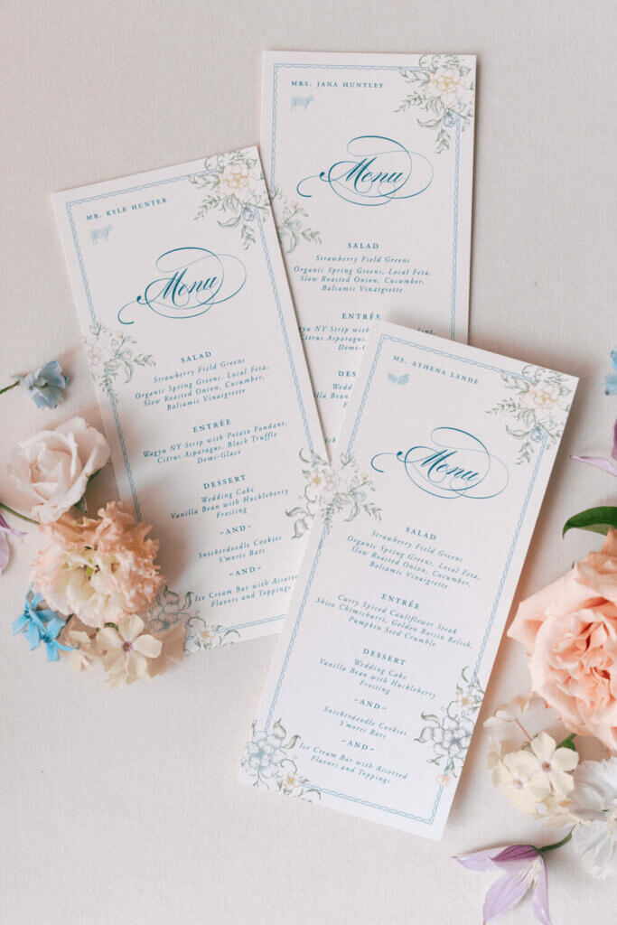 Flatlay of floral wedding menus surrounded by pastel flowers for a summer wedding at Moonlight Basin.