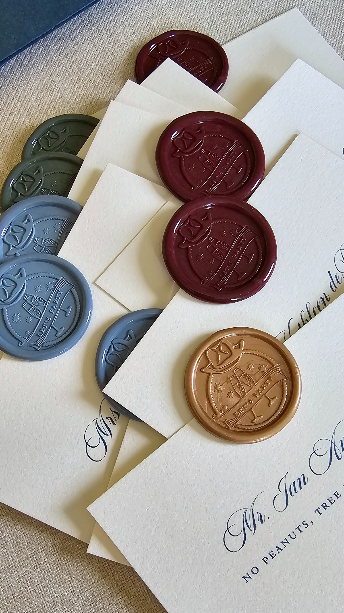 Colorful wax seals in burgundy, slate, and gold styled on cream cards, part of a custom Sage Lodge, Montana wedding paper suite.