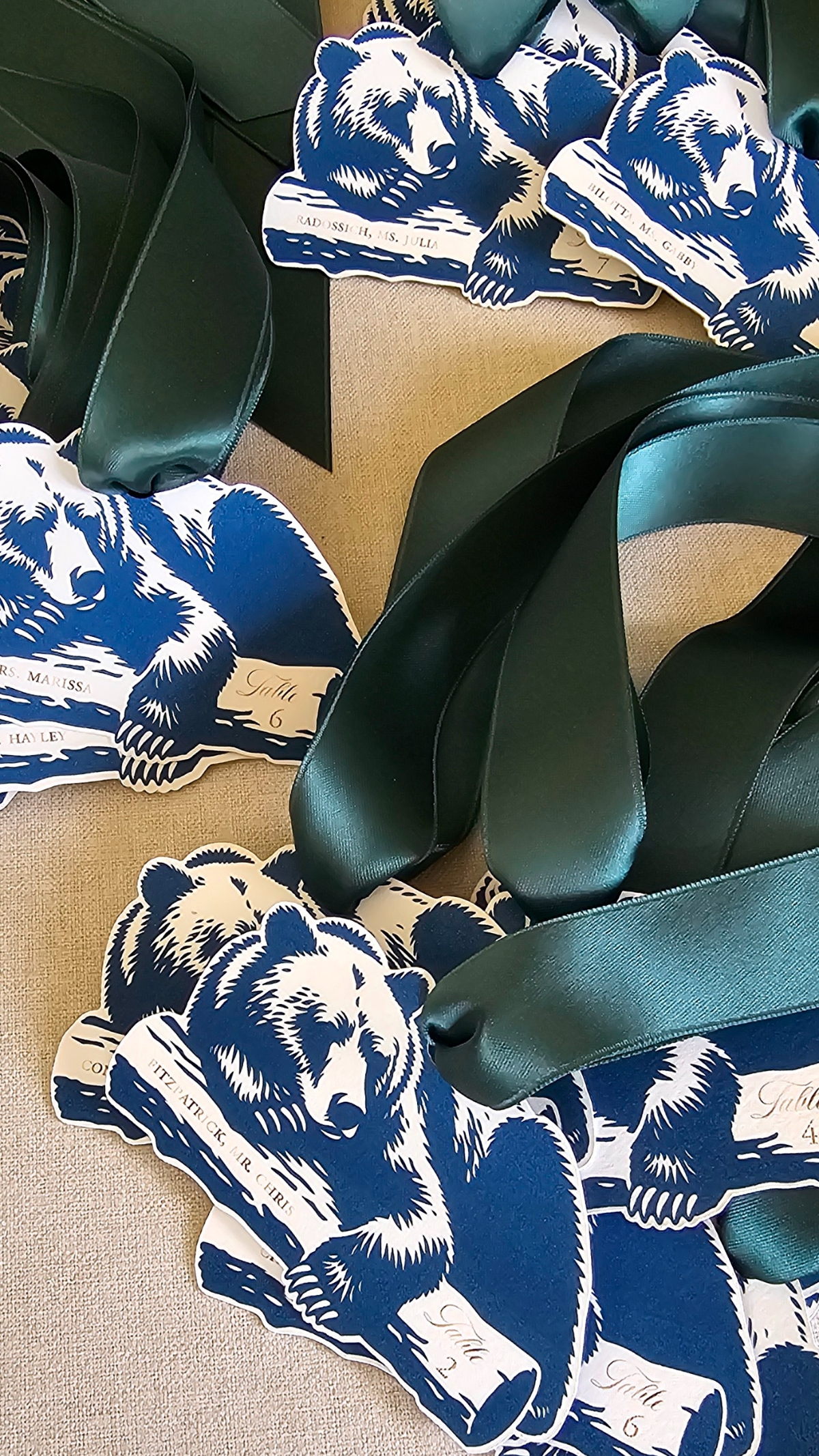 Blue bear-shaped escort cards with green satin ribbons for a Sage Lodge, Montana wedding with western-inspired stationery.