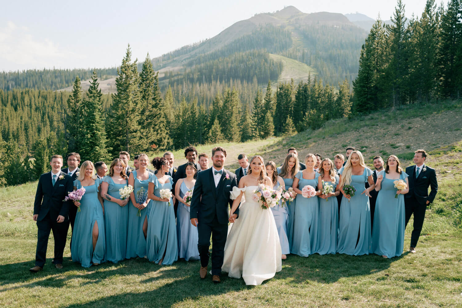 Wedding party portrait with bride, groom, bridesmaids in pastel blue dresses, and groomsmen at Moonlight Basin.