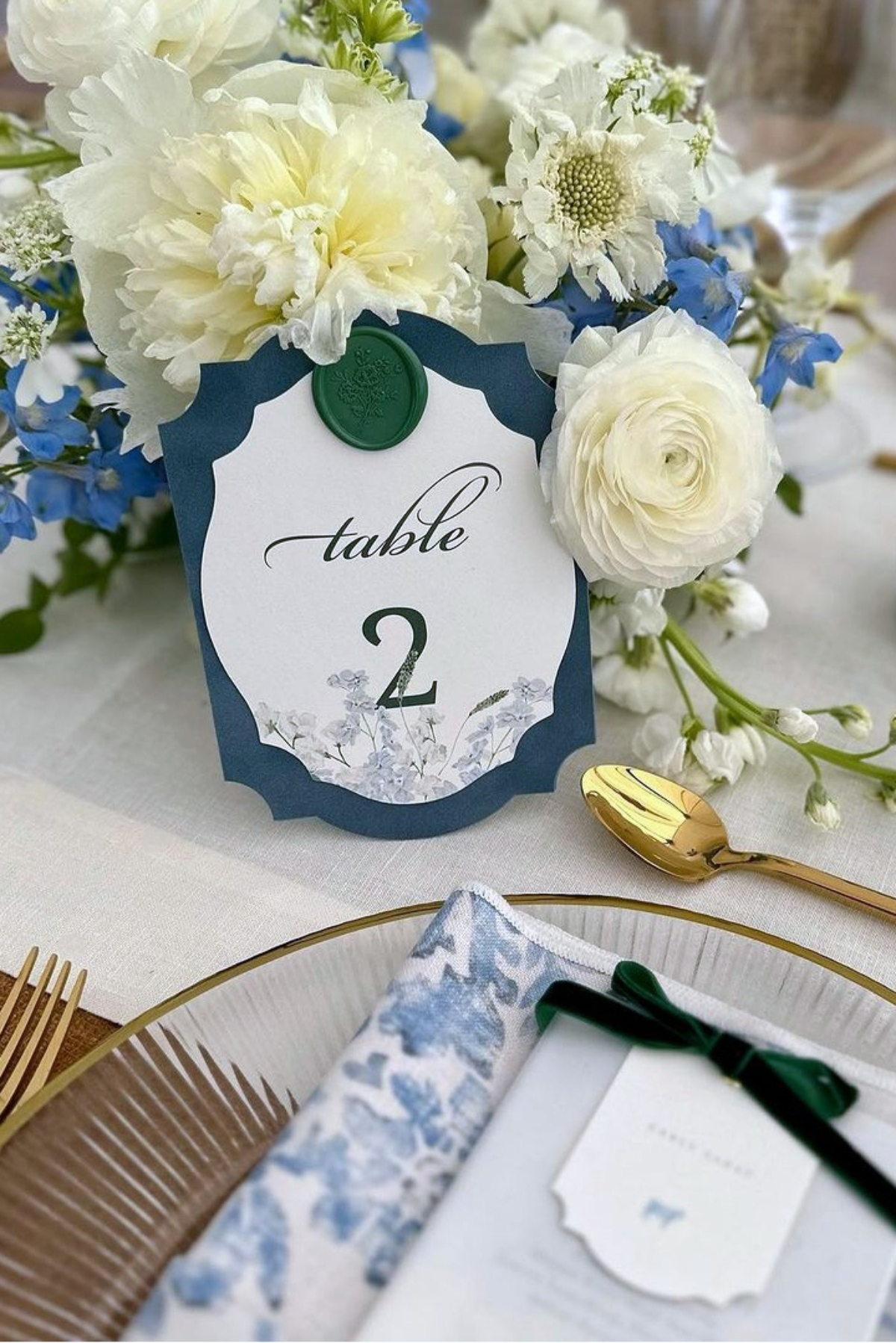 Choosing Your Wedding Invitation Style 13 Table number card with wax seal displayed among lush white and blue florals on a formal tablescape, coordinating with a romantic wedding invitatin style.