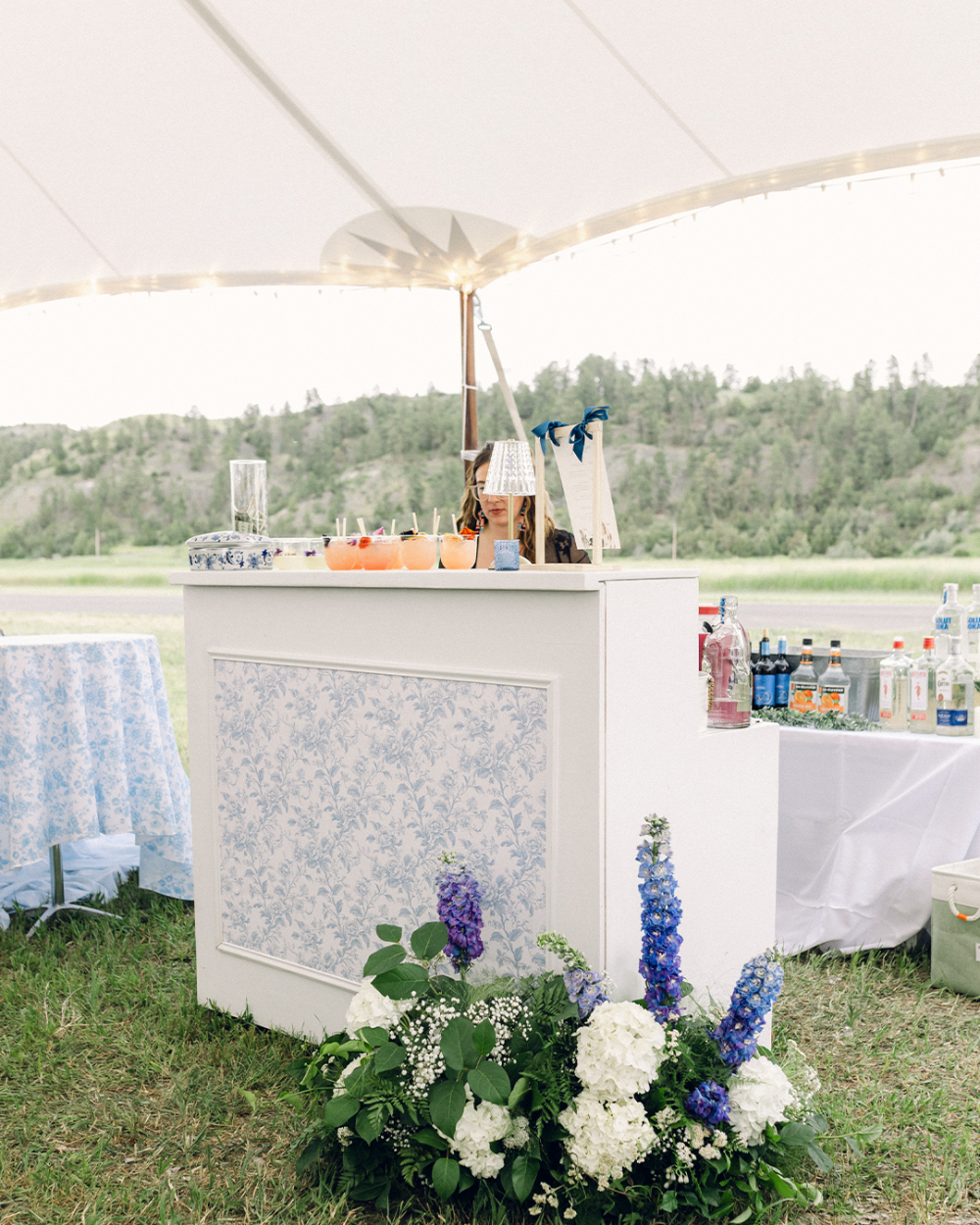 Custom wedding bar front with blue floral motif and large blue and white floral arrangement in the corner.