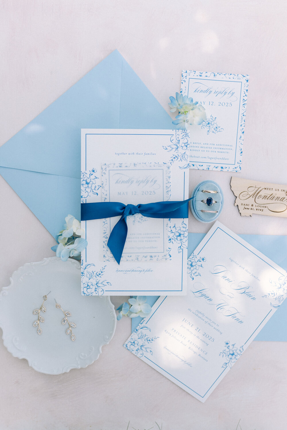 Blue and white garden party wedding invitation suite with floral details, silk ribbon, matching envelopes, reply card, and accessories styled on a soft neutral background | wedding guest experience